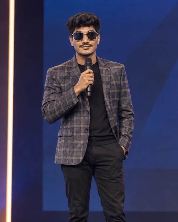 Niraj Ojha speaking on stage, holding a microphone.